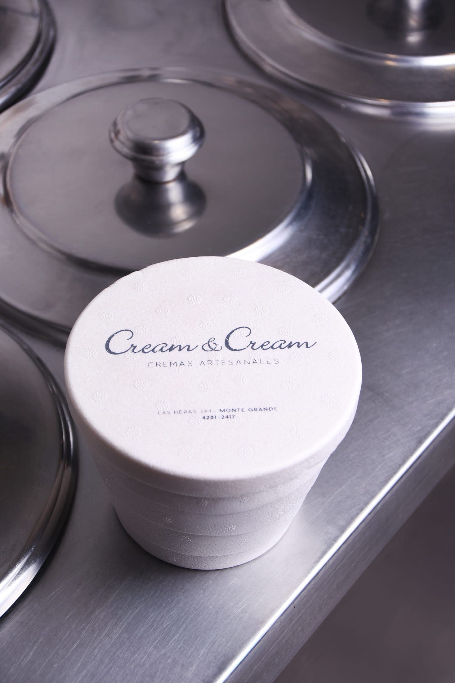 Pote de helado para llevar con la dirección del local impresa en la tapa